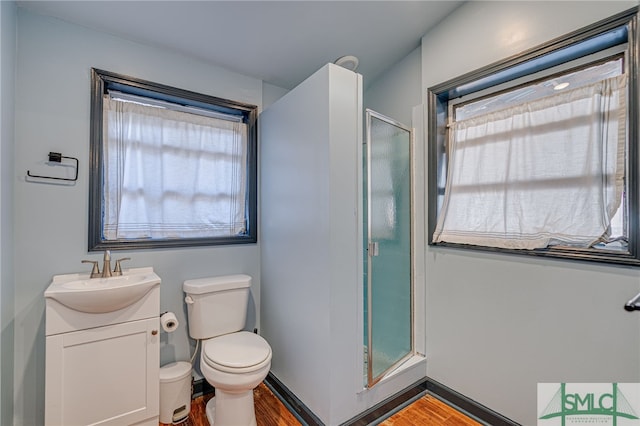 full bath with a stall shower, baseboards, toilet, wood finished floors, and vanity