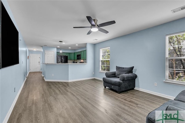 living room featuring visible vents, baseboards, and wood finished floors