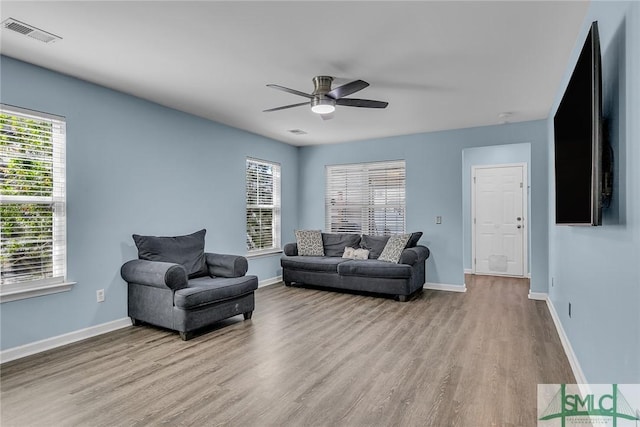 living area with visible vents, a ceiling fan, baseboards, and wood finished floors