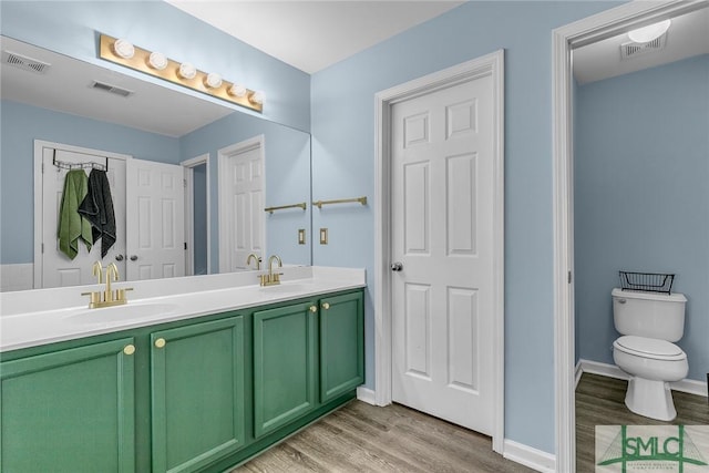 full bath featuring double vanity, wood finished floors, visible vents, and a sink