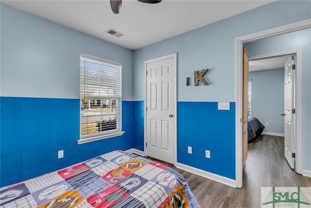 bedroom featuring visible vents, baseboards, wood finished floors, and a ceiling fan