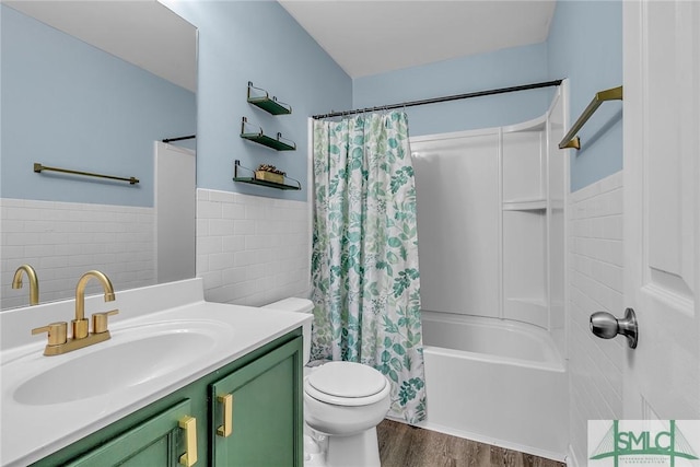 bathroom featuring toilet, vanity, wood finished floors, shower / bath combination with curtain, and tile walls