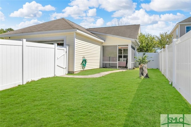 back of house featuring a garage, a lawn, a fenced backyard, and a sunroom