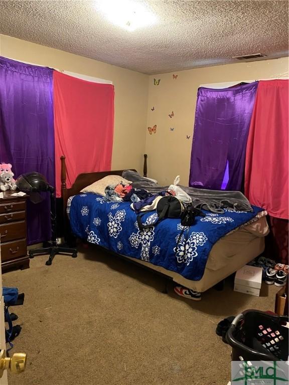 carpeted bedroom with visible vents and a textured ceiling