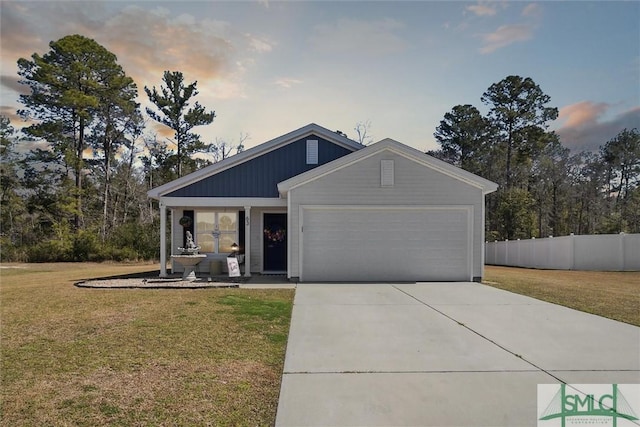 view of front of property featuring concrete driveway, a lawn, an attached garage, and fence