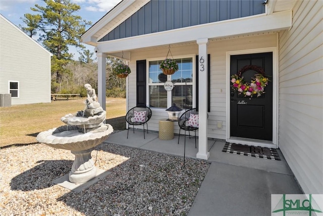 view of exterior entry featuring a yard, a porch, board and batten siding, and central AC unit