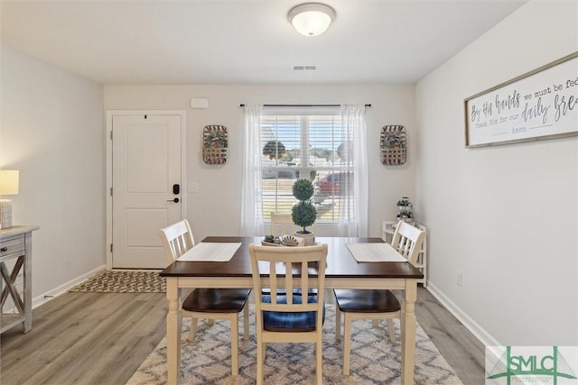 dining space with light wood-style floors, visible vents, and baseboards