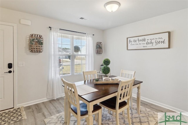 dining space with light wood-style flooring, visible vents, and baseboards