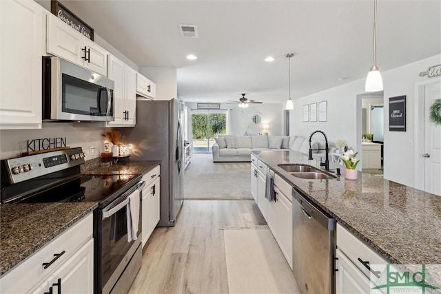 kitchen with visible vents, white cabinets, appliances with stainless steel finishes, open floor plan, and a sink