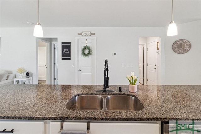 kitchen with pendant lighting, dark stone counters, and a sink