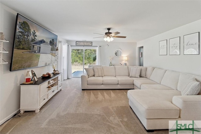 living area with baseboards, a ceiling fan, and light colored carpet