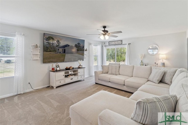 living room featuring baseboards, a ceiling fan, and light colored carpet