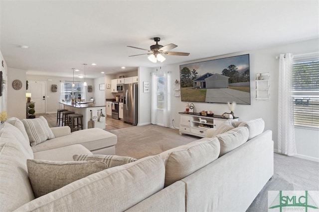 living area featuring a ceiling fan, light carpet, and baseboards