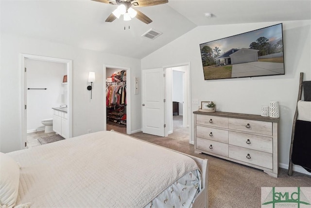 bedroom featuring a spacious closet, visible vents, vaulted ceiling, and light colored carpet