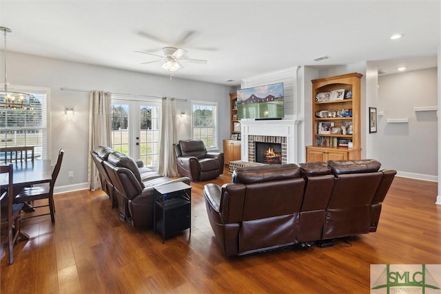 living area with a brick fireplace, baseboards, visible vents, and dark wood-type flooring