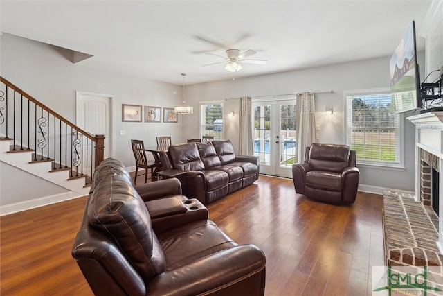 living area featuring baseboards, dark wood finished floors, stairs, french doors, and a fireplace