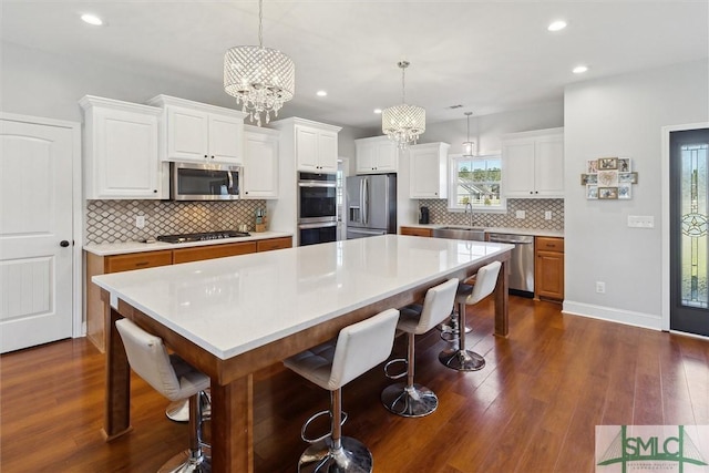 kitchen with a sink, an inviting chandelier, appliances with stainless steel finishes, and dark wood-style flooring