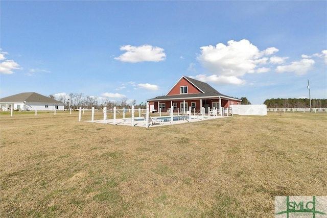 rear view of house with fence, a fenced in pool, and a yard