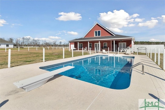 outdoor pool featuring french doors, a yard, a patio area, fence, and a diving board