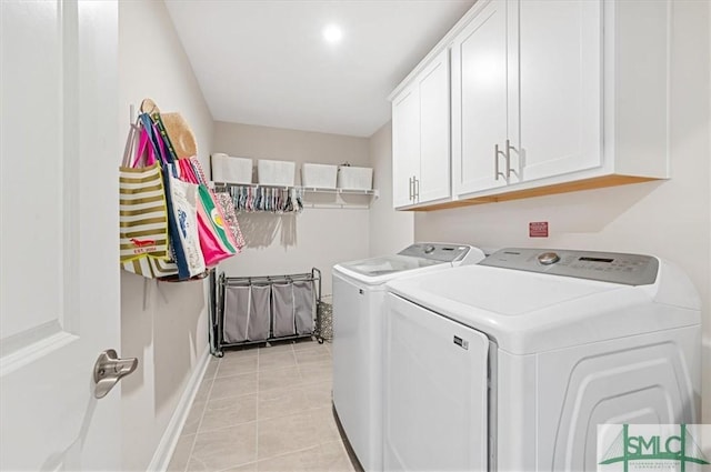 washroom with washer and clothes dryer, light tile patterned flooring, and cabinet space