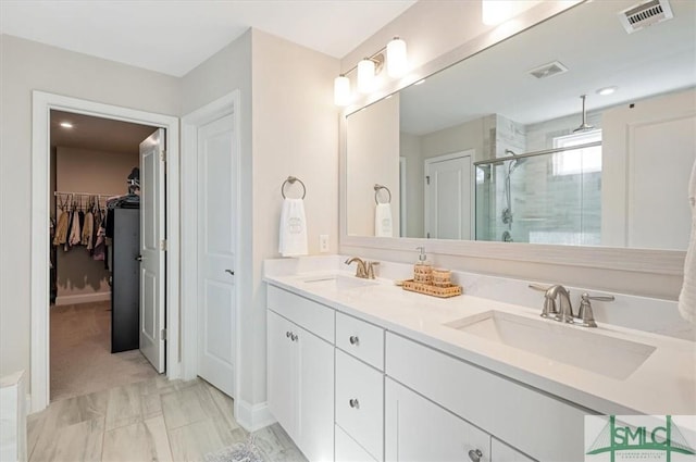 full bathroom with double vanity, a stall shower, a sink, and visible vents