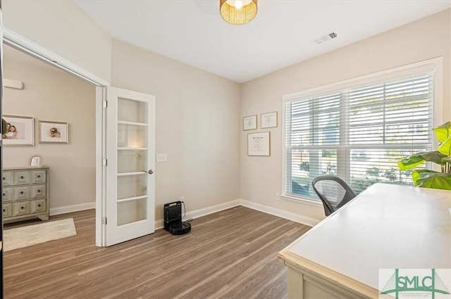 office space featuring wood finished floors, visible vents, and baseboards