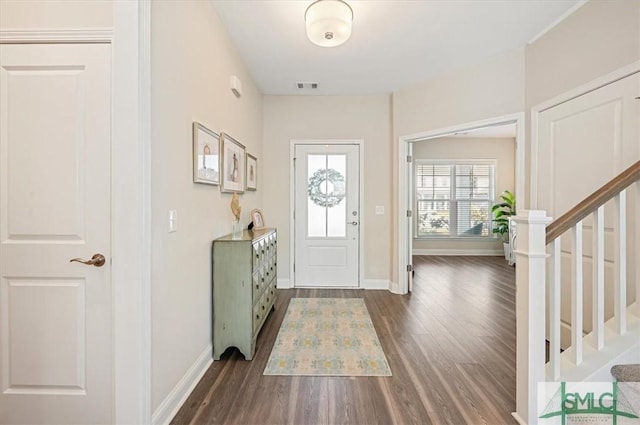 foyer entrance featuring dark wood-style floors, visible vents, stairway, and baseboards