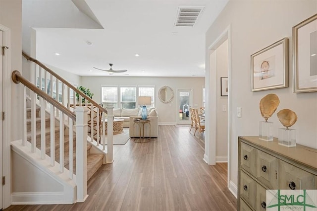 entryway featuring a ceiling fan, baseboards, stairs, visible vents, and light wood-style floors