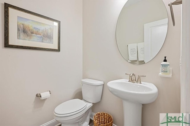 bathroom with baseboards, a sink, and toilet