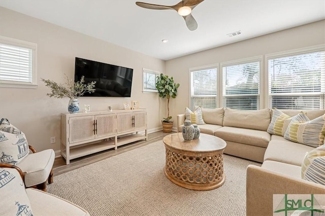 living room featuring visible vents, ceiling fan, baseboards, and wood finished floors