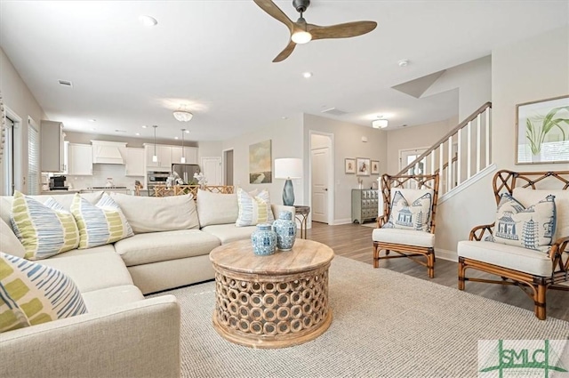 living room featuring light wood-type flooring, recessed lighting, baseboards, and stairs