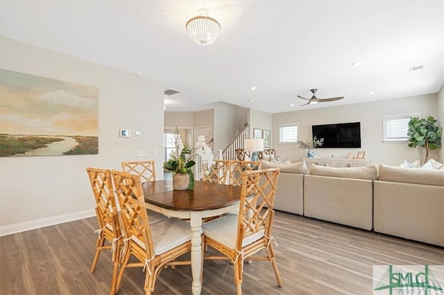 dining area featuring light wood-style floors, stairway, a healthy amount of sunlight, and visible vents