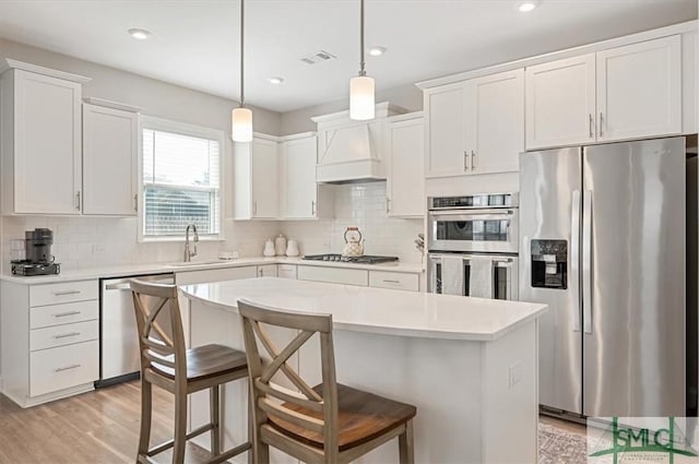 kitchen with light wood-style flooring, stainless steel appliances, visible vents, light countertops, and a center island