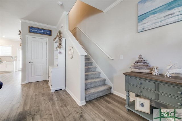 stairway with baseboards, wood finished floors, and crown molding