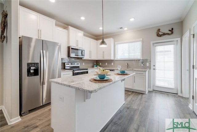 kitchen with stainless steel appliances, tasteful backsplash, a kitchen island, and white cabinetry