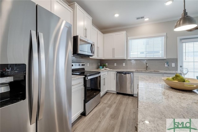 kitchen featuring tasteful backsplash, appliances with stainless steel finishes, a sink, and ornamental molding