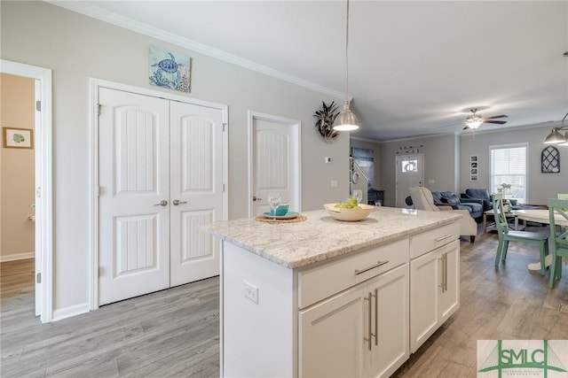 kitchen featuring ornamental molding, white cabinets, light wood-style floors, and a kitchen island