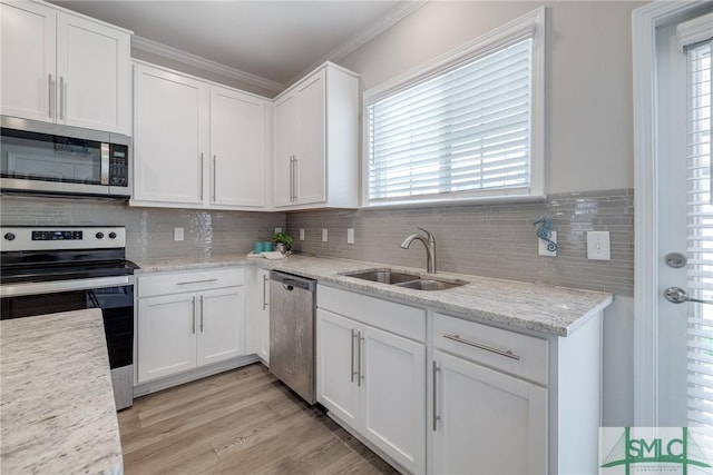 kitchen featuring appliances with stainless steel finishes, a wealth of natural light, white cabinets, and a sink