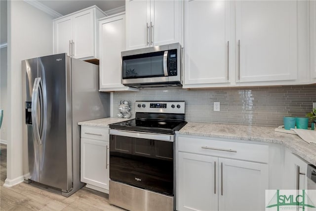 kitchen with white cabinets, light stone counters, appliances with stainless steel finishes, light wood-type flooring, and backsplash