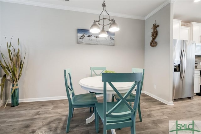 dining room featuring an inviting chandelier, baseboards, crown molding, and wood finished floors