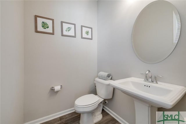 bathroom with baseboards, a sink, toilet, and wood finished floors