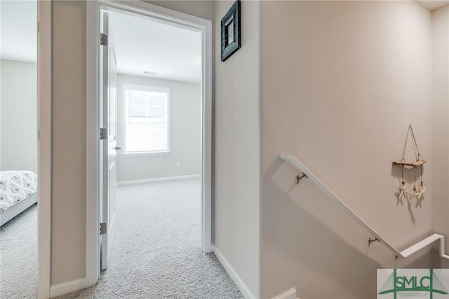 corridor with carpet floors, an upstairs landing, and baseboards