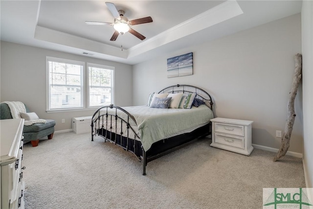 bedroom featuring light carpet, baseboards, visible vents, a raised ceiling, and a ceiling fan