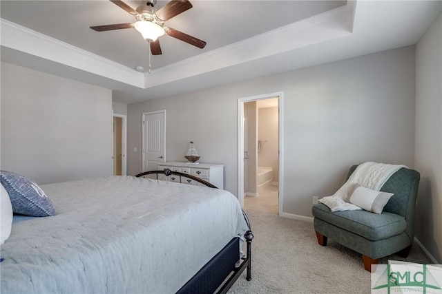 bedroom featuring ceiling fan, light colored carpet, baseboards, a tray ceiling, and ensuite bath