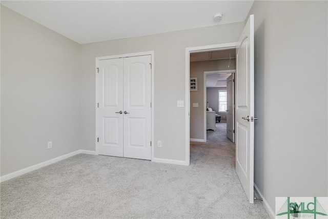 unfurnished bedroom featuring a closet, light carpet, and baseboards