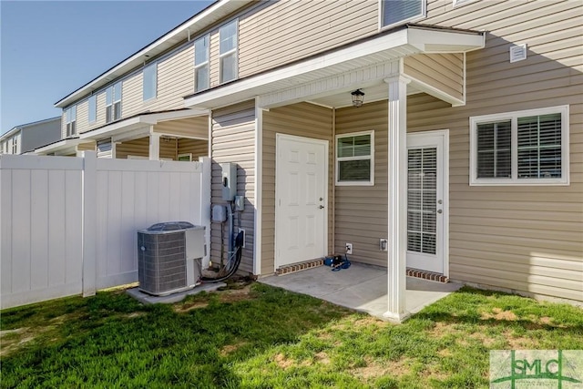 doorway to property featuring a yard, cooling unit, a patio area, and fence