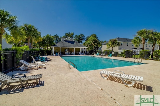 community pool with a patio area and fence