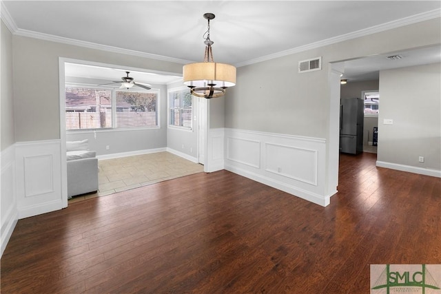 unfurnished dining area featuring a wainscoted wall, dark wood-style floors, visible vents, and ornamental molding