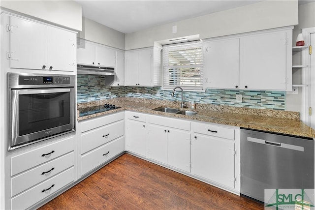 kitchen with dark wood finished floors, a sink, under cabinet range hood, appliances with stainless steel finishes, and white cabinetry