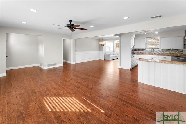 unfurnished living room with dark wood-style floors, visible vents, and ceiling fan